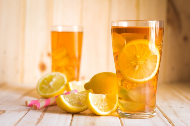 Bicchieri di tè freddo con fette di limone su fondo di legno