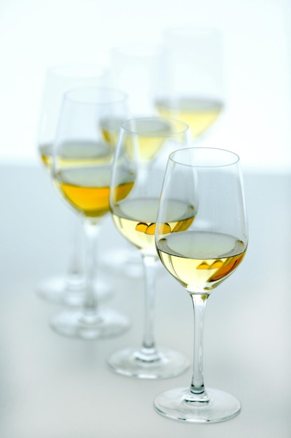 Bicchieri di vino con vino bianco sulla tavola di legno su sfondo luminoso