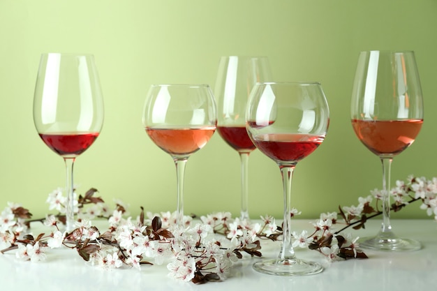 Bicchieri di vino e fiori di ciliegio su sfondo verde