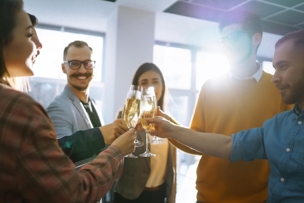 Bicchieri tintinnanti con champagne Colleghi felici che celebrano il loro successo aziendale