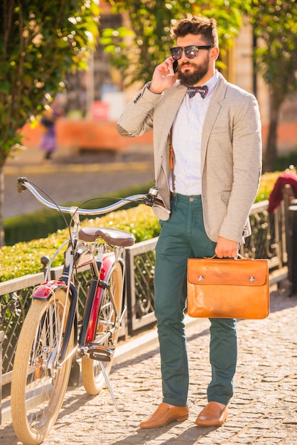 Bici da città. Un giovane con la barba, cammina per la città in bici