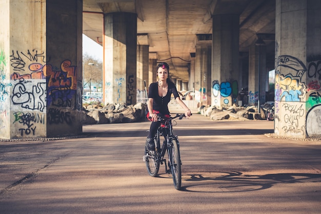 Bici di guida della giovane ragazza bella punk scura