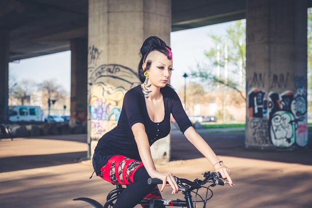 Bici di guida della giovane ragazza bella punk scura