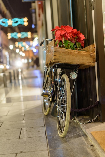 Bici retrò con lucine e una stella di Natale sul cesto in una strada decorata di Natale