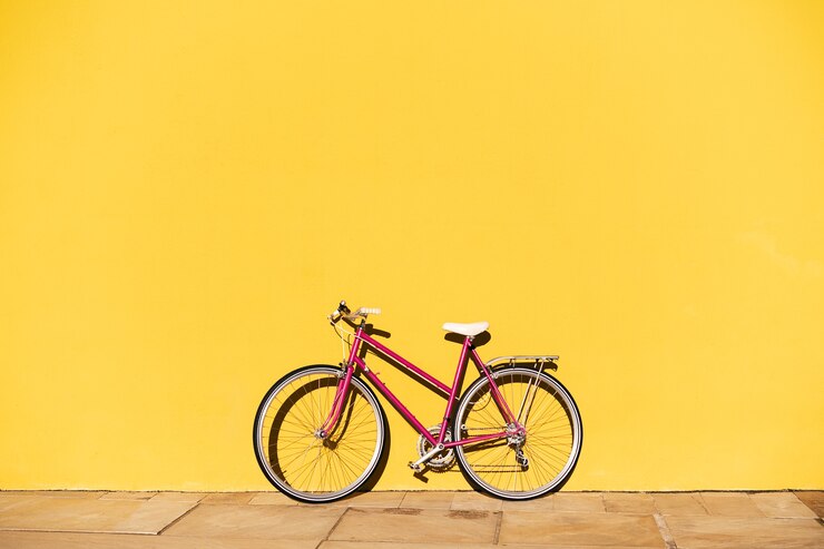 Bici retrò rosa supportata su una parete gialla