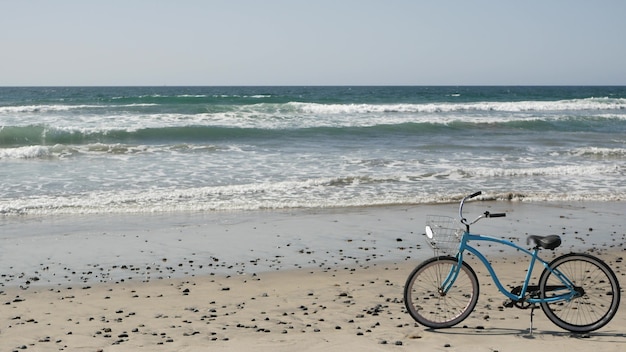 Bicicletta blu, bici da crociera, costa della spiaggia dell'oceano, California USA. riva del mare. ciclo sulla sabbia. onde d'acqua