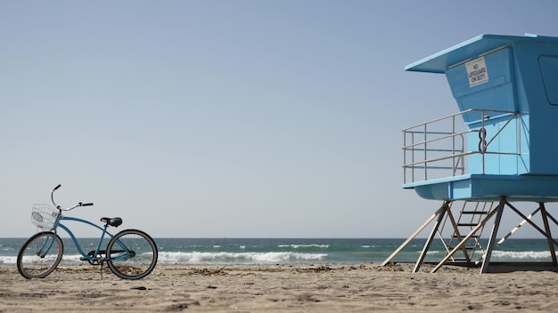 Bicicletta blu, bici da crociera sulla spiaggia dell'oceano, costa del Pacifico, California USA, riva del mare. torretta del bagnino