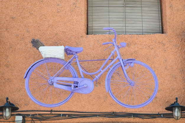 Bicicletta colorata sul muro. Decorazione esterna. Vita in bicicletta, arredamento moderno.