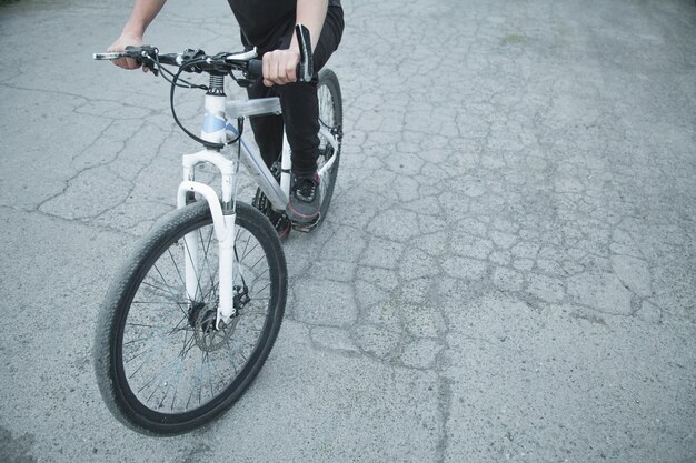 Bicicletta di guida del ragazzo caucasico all'asfalto.