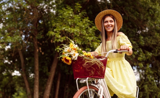 Bicicletta di guida della giovane donna affascinante in natura