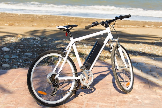 Bicicletta nera parcheggiata nella sabbia della spiaggia.