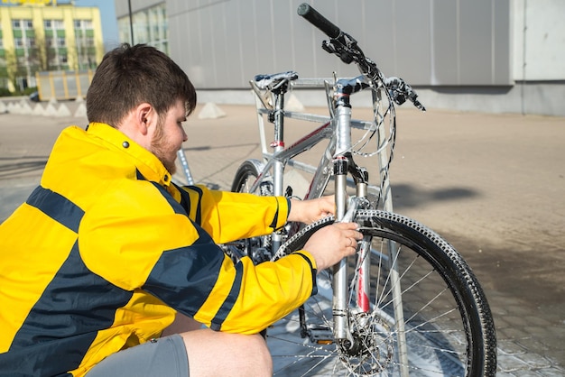 Bicicletta pulita del giovane con sapone e spugna allo stile di vita self-service dell'autolavaggio