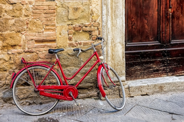 Bicicletta rossa appoggiata a un muro a Pienza