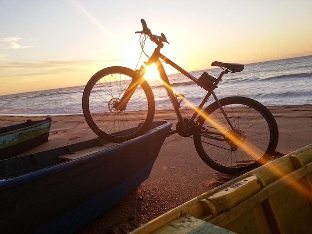 Bicicletta su una barca sulla spiaggia durante il tramonto