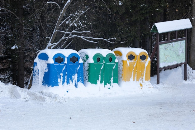 Bidoni della spazzatura multicolori per il riciclaggio e i rifiuti domestici, in inverno nella neve