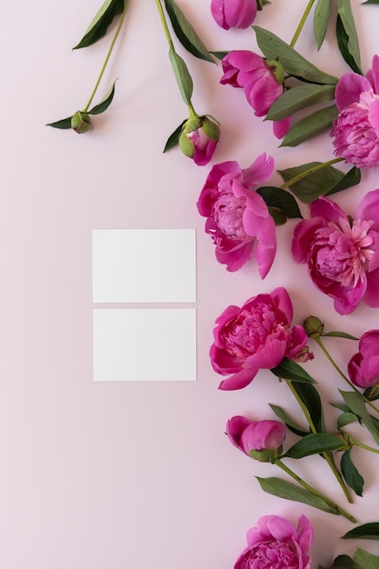 Biglietti d'invito in carta bianca con spazio per la copia Bouquet di fiori di peonia rosa su sfondo rosa elegante pastello neutro Composizione floreale minima con vista dall'alto piatta