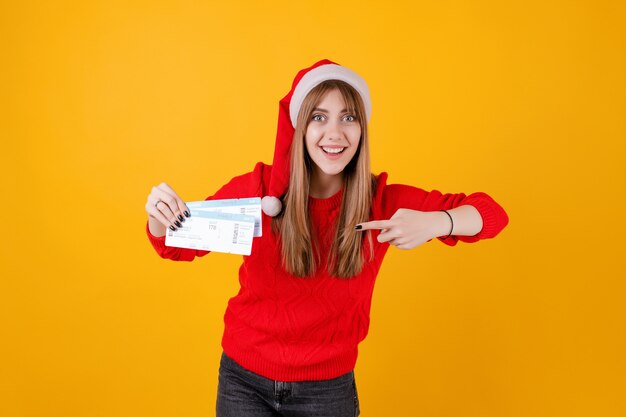 Biglietti di aeroplano felici della tenuta della donna che portano il cappello di Santa