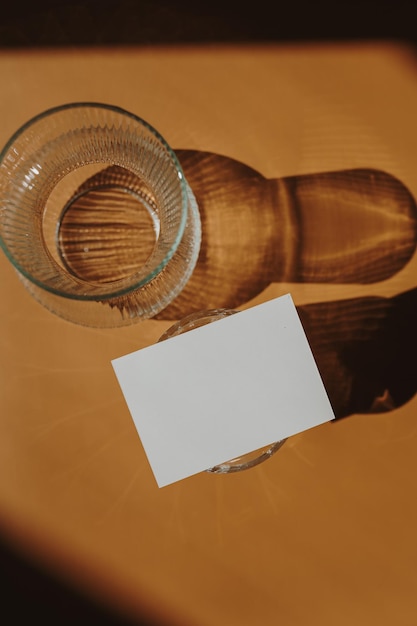 Biglietto d'invito in carta bianca con spazio per la copia Riflessi dell'ombra della luce solare su uno sfondo arancione caldo e marrone chiaro Inviti di nozze minimalisti estetici con vista dall'alto piatta