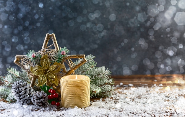 Biglietto di auguri con una stella di Natale decorata, una candela accesa, rami di abete innevati e coni