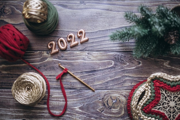 Biglietto di auguri di Natale e Capodanno 2022, gomitoli di filato lavorato a maglia, uncinetto e cesto lavorato a maglia su un tavolo di legno, vista dall'alto