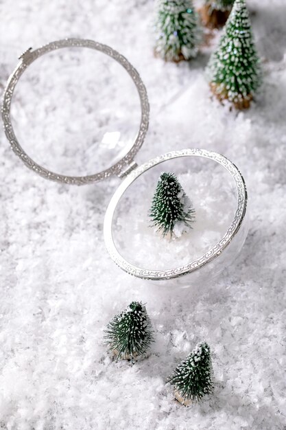 Biglietto di auguri di Natale o Capodanno. Il vetro ha aperto l'abete trasparente della decorazione della sfera all'interno con gli alberi di Natale decorativi intorno sul fondo della neve. Atmosfera natalizia
