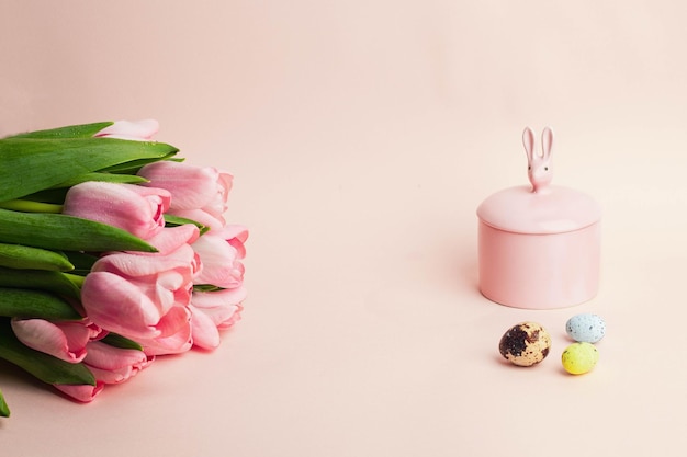 Biglietto di auguri di Pasqua bouquet di tulipani rosa con set di varios pastello colorati egss pasquali e coniglio rosa di pasqua su sfondo rosa sfondo pasquale vista dall'alto con copyspace