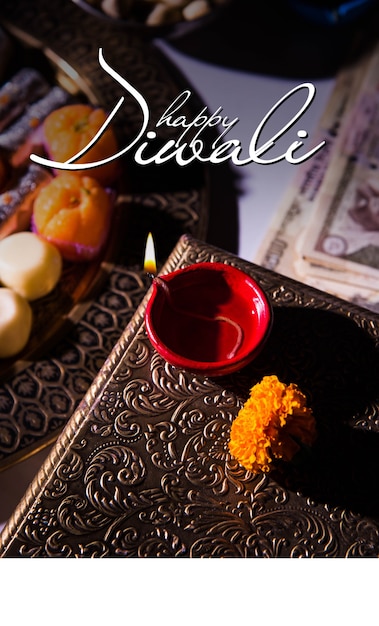 Biglietto di auguri Diwali felice che mostra lampada a olio o diya con petardi, Mithai, frutta secca, banconote indiane, fiori di calendula e statua della dea Laxmi o Lakshmi