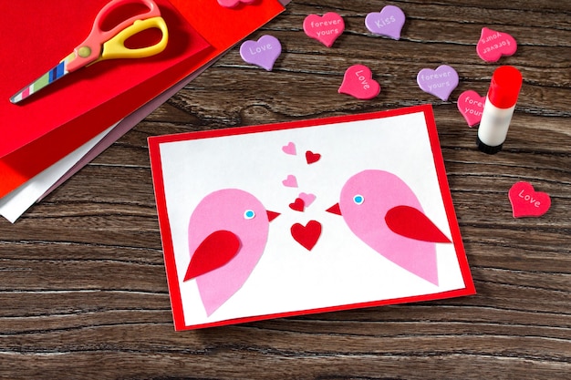 Biglietto di auguri per bambini Due uccelli e cuore da una carta il giorno di San Valentino.