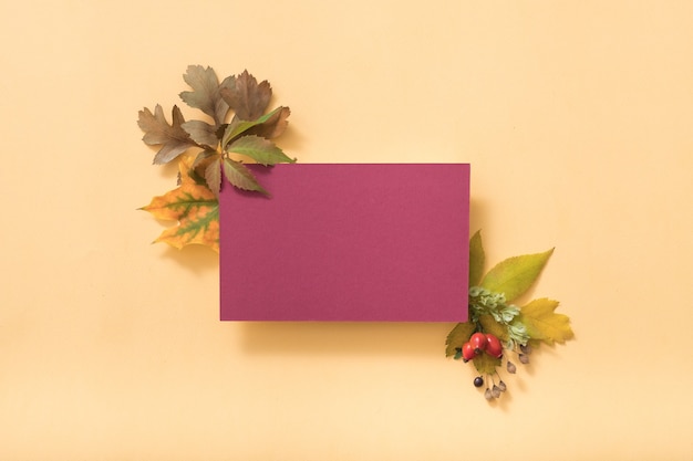 Biglietto di auguri viola vuoto o nota di carta con foglie autunnali, vista dall'alto