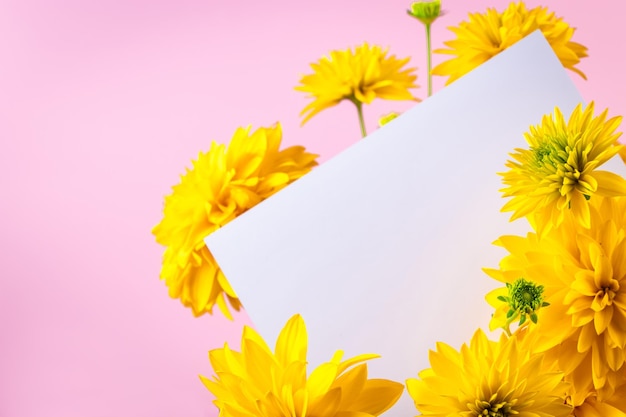 Biglietto di auguri vuoto in un bouquet di fiori gialli estivi su sfondo rosa Consegna fiori