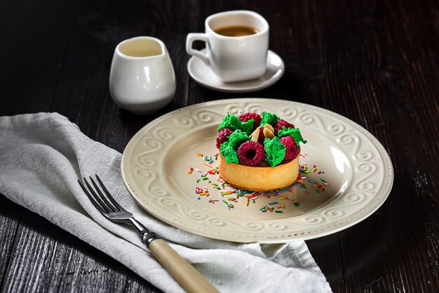 Bigné delizioso con frutti di bosco sul tavolo. Una tazza di caffè e una torta su un piatto bianco