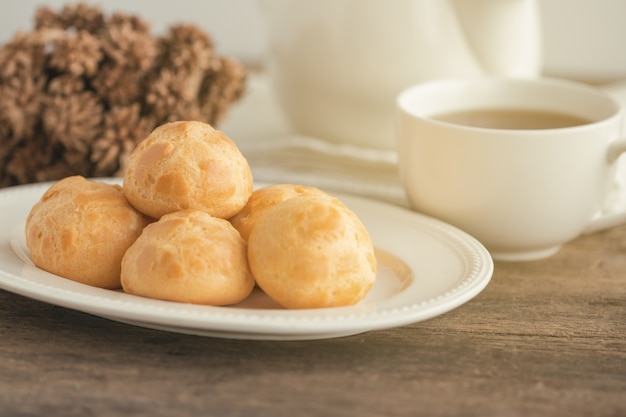 Bignè fatti in casa o eclair o crema di choux servito con tè sul tavolo di legno.