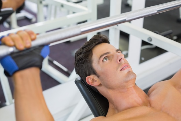 Bilanciere di sollevamento dell&#39;uomo muscolare senza camicia in palestra