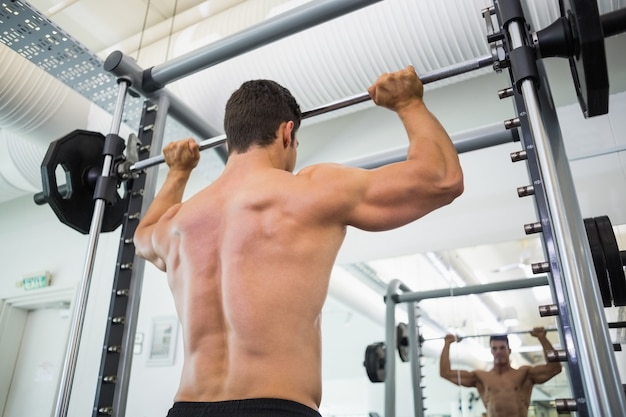 Bilanciere di sollevamento dell&#39;uomo muscolare senza camicia in palestra