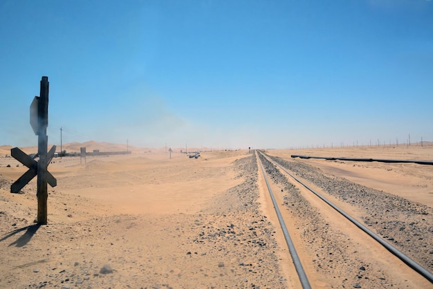 Binari ferroviari nel deserto in prospettiva nella sabbia infinita sullo sfondo del blu