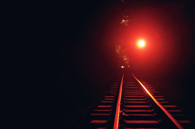 Binario ferroviario di notte. la luce rossa è accesa.