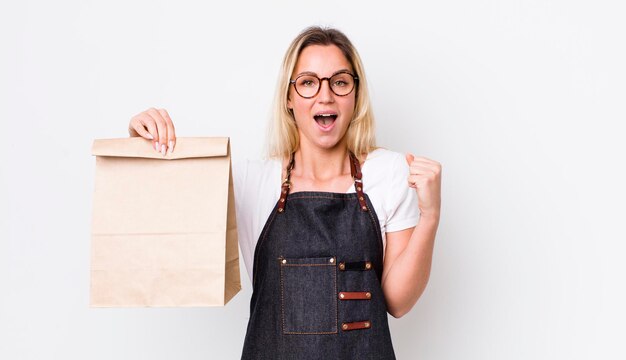 Bionda bella donna che si sente scioccata e ride e celebra la consegna del successo porta via il concetto