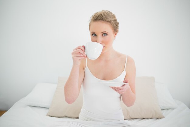 Bionda contenta naturale che beve da una tazza