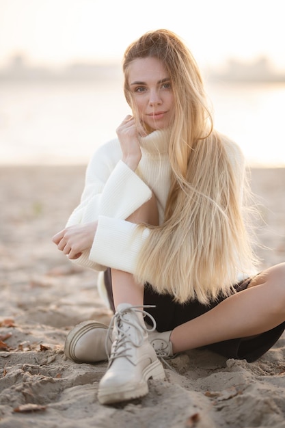 Bionda dai capelli lunghi sulla riva del fiume La ragazza felice si rilassa in una giornata autunnale