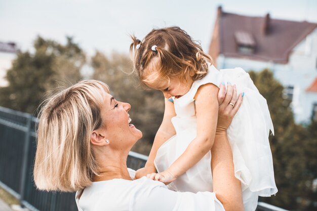 Bionda di mamma che tiene una piccola figlia nel parco in estate