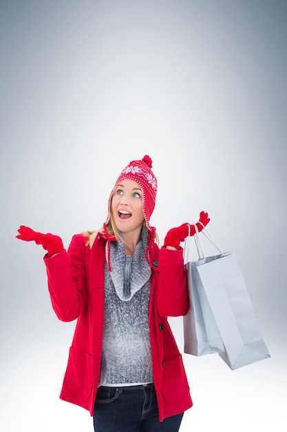 Bionda felice in vestiti di inverno che tengono i sacchetti della spesa