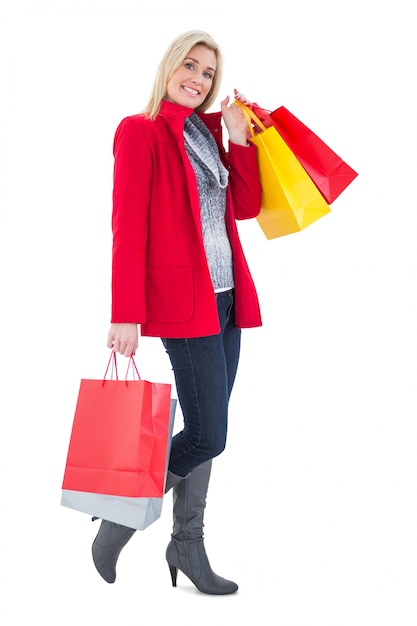 Bionda felice in vestiti di inverno che tengono i sacchetti della spesa