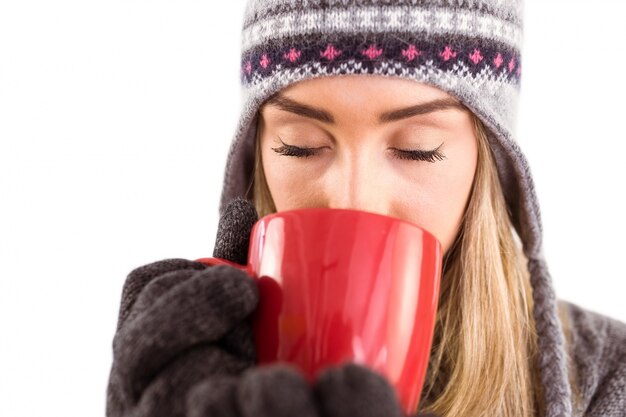 Bionda felice in vestiti di inverno che tiene tazza