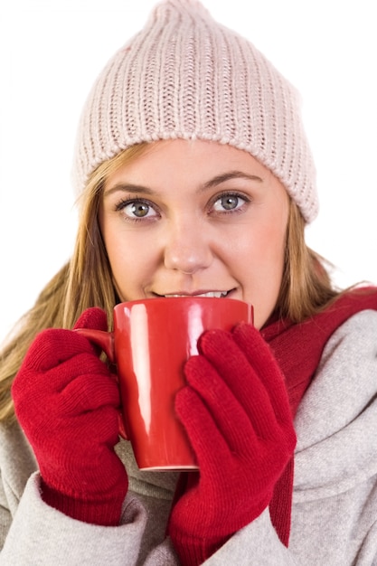 Bionda felice in vestiti di inverno che tiene tazza