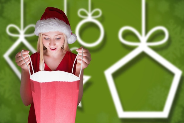 Bionda festosa che apre un sacchetto regalo su sfondo natalizio sfocato