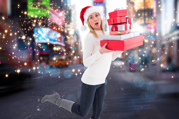 Bionda festosa che tiene un mucchio di regali contro la sfocata strada di New York