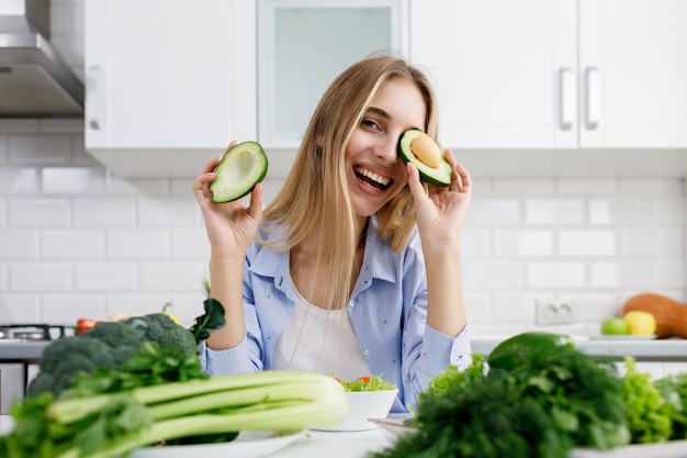 Bionda giocosa in posa con metà di avocado