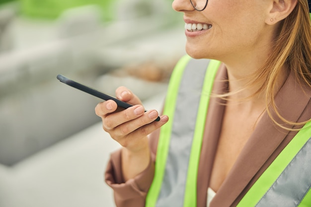 bionda giovane donna caucasica in occhiali rotondi usando il suo telefono cellulare