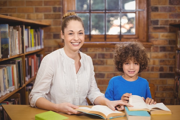 Bionda insegnante e allievo lettura libri in biblioteca