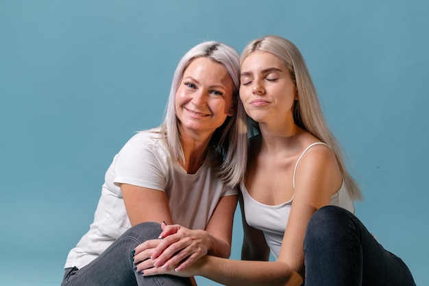 Bionda mamma e figlia adolescente sorridente su sfondo colorato studio sparare con copia spazio